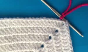 Joining granny square with slip stitch attaching slip knot to first granny square