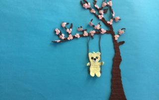 Finished crochet blossoms and swing bright blue background with teddy landscape